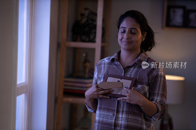 Portrait to Indian woman holding photo frame memories at home stock photo